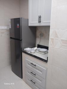 a kitchen with a black refrigerator and white cabinets at First MEN in Salalah +37 photos