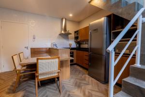 a kitchen with a dining table and a refrigerator at Novo Bhaus Gaudi Campos do Jordão Loft Duplex - Linda Vista - 600m do Capivari in Campos do Jordão