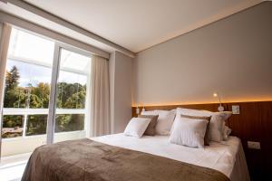 a bedroom with a large bed with a large window at Novo Bhaus Gaudi Campos do Jordão Loft Duplex - Linda Vista - 600m do Capivari in Campos do Jordão +62 photos