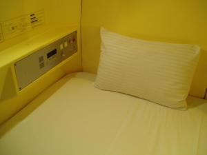 a bed with a white blanket on top of it at Capsule Hotel & Sauna Ikebukuro Plaza in Tokyo