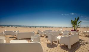a sandy beach with white chairs and tables on it at RH Bayren Hotel & Spa 4* Sup in Gandía