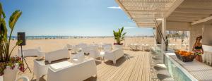 a beach restaurant with white chairs and a sandy beach at RH Bayren Hotel & Spa 4* Sup in Gandía