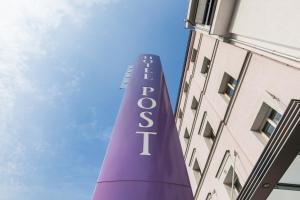 アシャッフェンブルクにあるNovum Hotel Post Aschaffenburgの建物の隣のオベリスクを読む紫色の看板