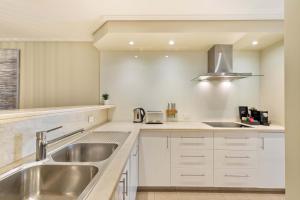 a kitchen with white cabinets and a stainless steel sink at Mirage Resort Villa 428 with access to Sheraton Facilities in Port Douglas
