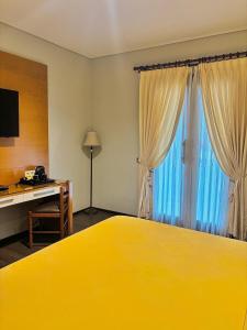 a hotel room with a yellow bed and a desk at COZY Boutique Guest House in Malang