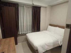 um quarto com uma cama branca e uma janela em WE Hotel Kowloon em Hong Kong
