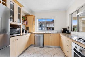 eine große Küche mit Holzschränken und einem Fenster in der Unterkunft Lakeside Luxe Retreat - Pool View BBQ Spa Bath in Cairns North