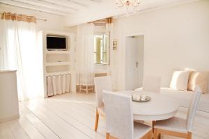 biała jadalnia z białym stołem i krzesłami w obiekcie Altana Boutique Hotel w mieście Tinos