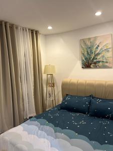 a bedroom with a bed with blue sheets and curtains at Our Gentle Nest at Batulao in Calo +11 photos