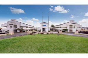 un gran edificio con un campo verde delante de él en Studio 6 Irving, TX - Irving DFW Airport East, en Irving