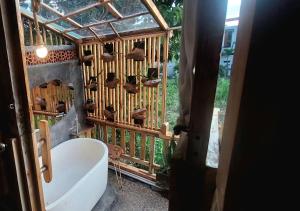 a bathroom with a tub and a wooden wall at Wisnu Lumbung Uluwatu in Uluwatu