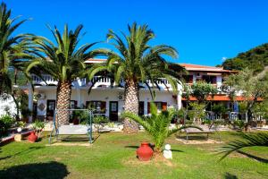 a resort with palm trees in the yard at Pelagos Beachfront in Panormos Skopelos