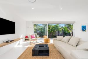 a living room with a white couch and a flat screen tv at Modern Coastal Escape - Stylish 3 BR Home with Pool in Byron Bay