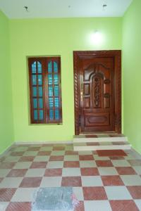 an empty room with a wooden door and a checkered floor at Shalom Inn in Tiruvannāmalai