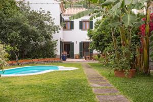 een huis met een zwembad in een tuin bij Casa do Lugar de Baixo in Ponta do Sol