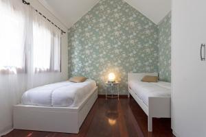 two beds in a bedroom with floral wallpaper at Casa do Lugar de Baixo in Ponta do Sol +12 photos
