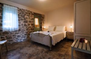 a bedroom with a bed and a brick wall at Palaeopoli Villas in Avlemonas