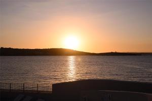 a sunset over a body of water with the sun setting at DoubleTree by Hilton Malta in St Paul's Bay