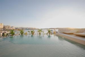a swimming pool with a view of the water at DoubleTree by Hilton Malta in St Paul's Bay