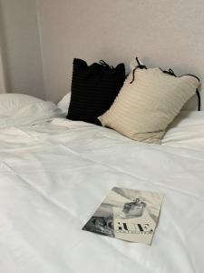 a book on top of a white bed with pillows at Station House Daechi in Seoul