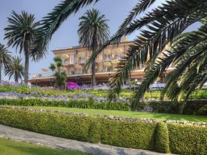 a building with palm trees in front of a garden at Hotel Continental in Santa Margherita Ligure
