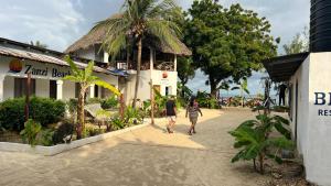 two people walking down a sidewalk in front of a building at Zanzi beach hotel in Nungwi