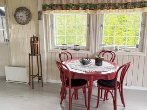 a red table and chairs in a room with a clock at 8 person holiday home in frosta in Vollen