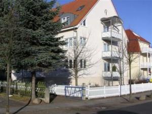 ein großes weißes Gebäude mit einem Baum davor in der Unterkunft Appartementhaus Ulmenhof in Kühlungsborn