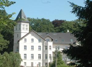 ein weißes Gebäude mit einem Turm darüber in der Unterkunft Appartement Schloß - Hohen Niendorf in Hohen Niendorf
