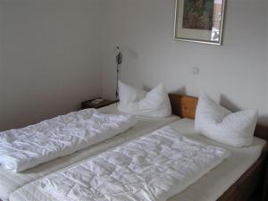 Una cama con sábanas blancas y almohadas. en Appartementhaus Gegenkolonnaden en Kühlungsborn