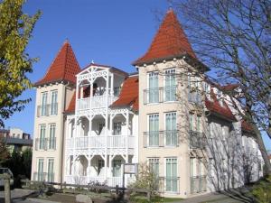 ein großes weißes Gebäude mit rotem Dach in der Unterkunft Appartementhaus Ulmenschloesschen in Kühlungsborn