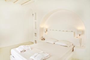 a white bedroom with a bed with two towels on it at Altana Boutique Hotel in Tinos