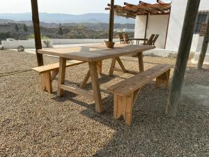 a wooden picnic table and a bench on a patio at Cortijo MAMANGUEÑA PISCINA Y CUEVA in Tabernas
