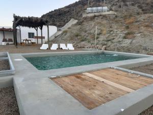 a pool with a wooden floor and chairs in at Cortijo MAMANGUEÑA PISCINA Y CUEVA in Tabernas