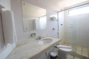 a bathroom with a sink and a toilet and a mirror at Pousada Baía Dos Corais in Tamandaré