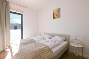 een witte slaapkamer met een bed en een raam bij Bałtyckie Tarasy by Q4Apartments in Władysławowo