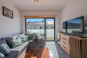 een woonkamer met een bank en een flatscreen-tv bij Bałtyckie Tarasy by Q4Apartments in Władysławowo
