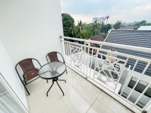 ein Balkon mit Tisch und Stühlen auf einem Gebäude in der Unterkunft Mataram City 327 by We Stay in Kejayan
