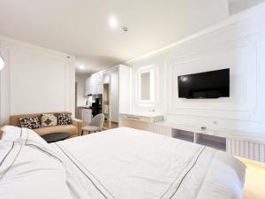 ein weißes Schlafzimmer mit einem Bett und einem Fernseher an der Wand in der Unterkunft Mataram City 327 by We Stay in Kejayan