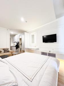 ein weißes Schlafzimmer mit einem Bett und einem TV an der Wand in der Unterkunft Mataram City 327 by We Stay in Kejayan