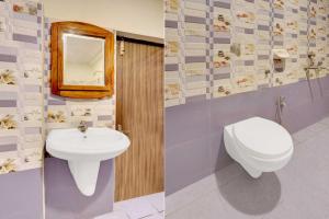 ein Badezimmer mit Waschbecken, Toilette und Spiegel in der Unterkunft Collection O Vijaywada Railway Stadium in Vijayawāda + 15 Fotos