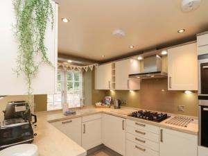 a kitchen with white cabinets and a stove top oven at Clematis Cottage in Whitby