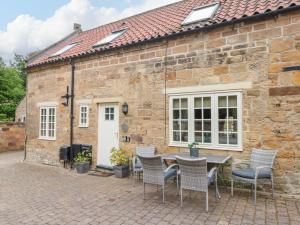 a stone cottage with a table and chairs in front of it at Clematis Cottage in Whitby