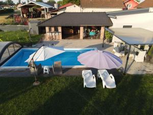 an umbrella and chairs next to a swimming pool at Ferienhaus Rovine in Ivišovo Greblje
