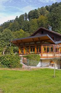 une grande maison avec une grande terrasse couverte dans un champ dans l'établissement Hotel Au Vieux Moulin, à Graufthal