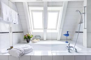 ein weißes Bad mit einer Badewanne und einem Fenster in der Unterkunft Boutique Hotel Seegarten in Zürich