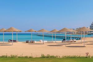 a beach with straw umbrellas and chairs and the ocean at Scandic Resort in Hurghada, EGYPT in Hurghada