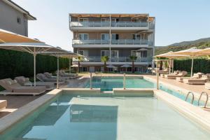 a swimming pool with chairs and umbrellas next to a building at Astra Sarti Luxury Suites in Sarti