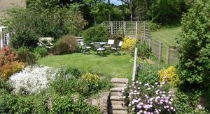 a garden with a table and chairs and flowers at Budleigh Farm Cottages in Moretonhampstead