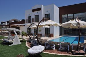 una piscina con sillas y sombrillas junto a un edificio en Small Beach Hotel en Turgutreis